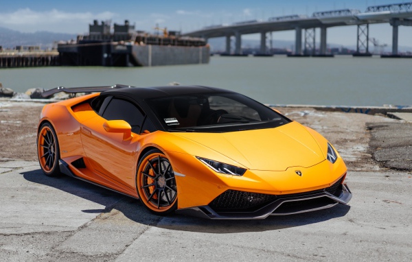 Оранжевый быстрый Lamborghini Huracan в порту у воды
