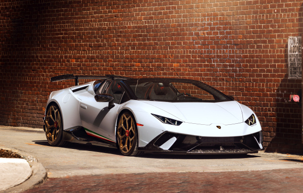 Белый быстрый Lamborghini Huracan стоит у кирпичной стены