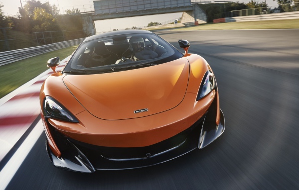 Спортивный оранжевый автомобиль McLaren 600LT 2019 года на трассе