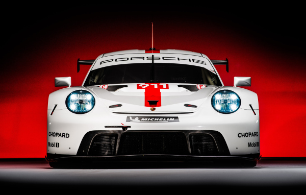 Спортивный автомобиль Porsche 911 RSR 2019 года на красном фоне