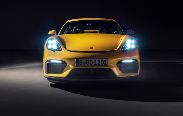 Автомобиль Porsche 718 Cayman GT4,  2019 года с включенными фарами 