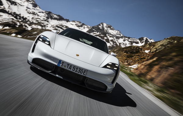 Белый автомобиль Porsche Taycan Turbo S 2019 года на фоне заснеженных гор