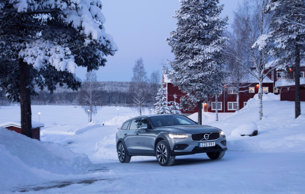 Автомобиль Volvo V60 на фоне заснеженных деревьев 