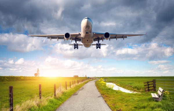 Пассажирский самолет взлетает над полем 