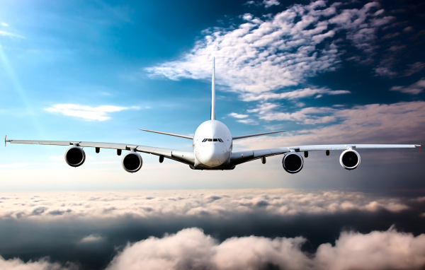 Самолет в белых облаках на фоне голубого неба