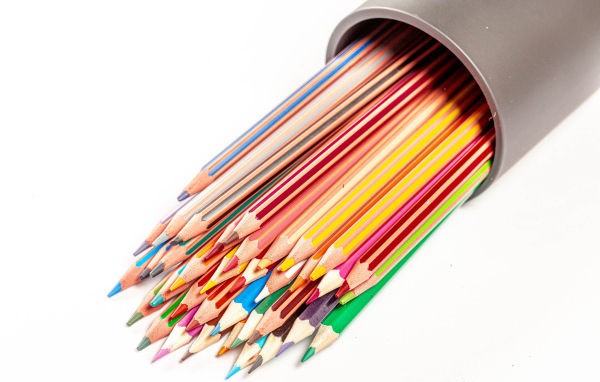 Много разных карандашей в пенале на белом фоне