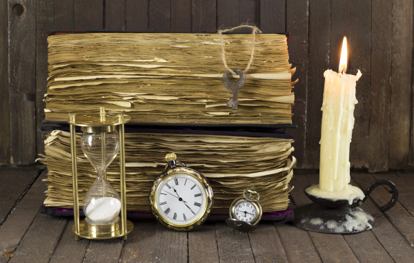 Старинные книги, зажженная свеча, ключи и часы на столе