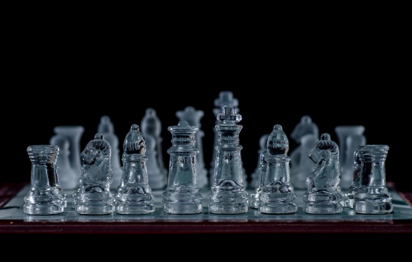 Стеклянные шахматы на доске на черном фоне
