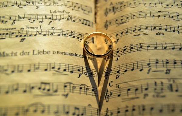 Золотое обручальное кольцо лежит на нотной тетради