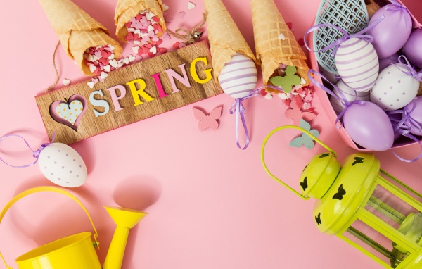 Надпись весна с вафельными рожками и яйцами на розовом фоне