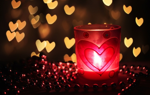 Зажженная свеча на столе с бусами 