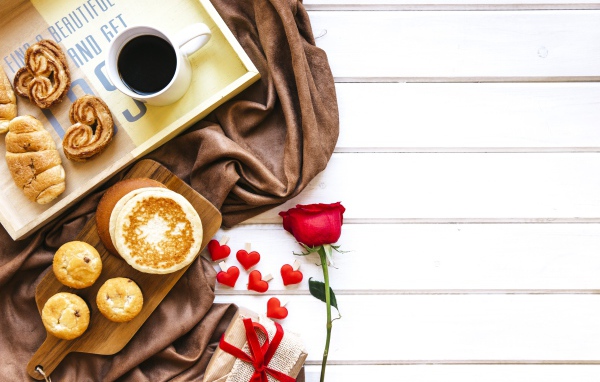 Выпечка на столе с кофе, подарком и красной розой