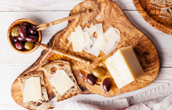 Сыр на доске с хлебом и и оливками