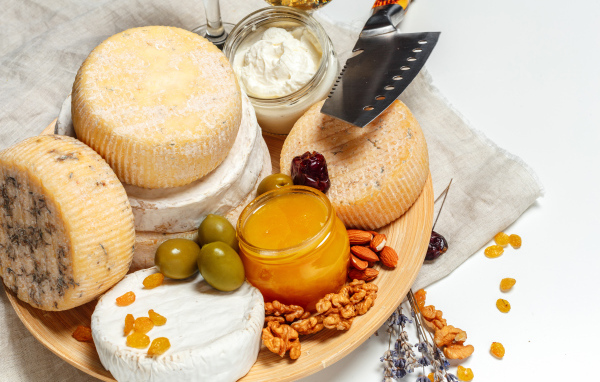 Сыр с плесенью на тарелке оливками, орехами и медом 