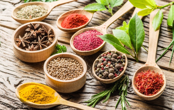 Разные специи в деревянных ложках на столе 