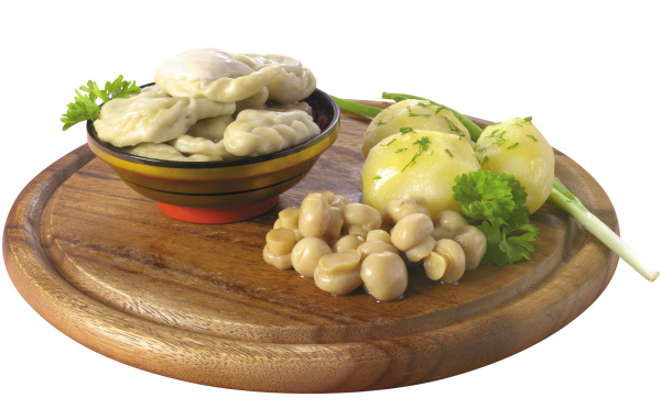 Вареники с грибами и вареной картошкой на деревянной доске на белом фоне