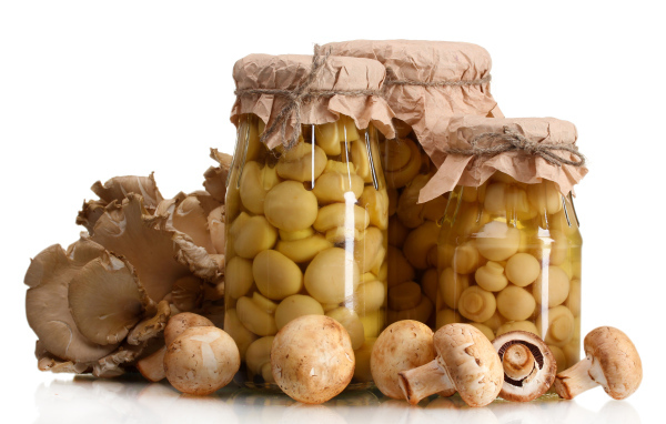 Маринованные шампиньоны в банках на белом фоне со свежими