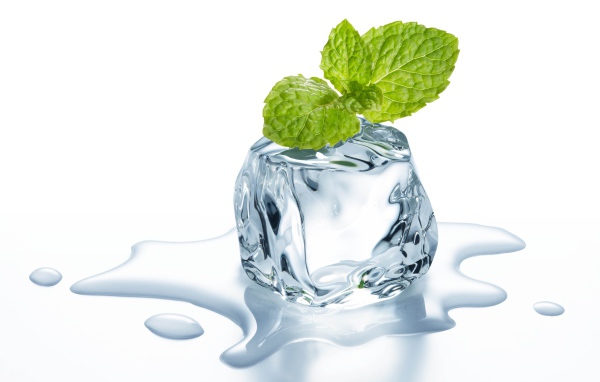 Тающий кубик льда с листиком мяты на белом фоне