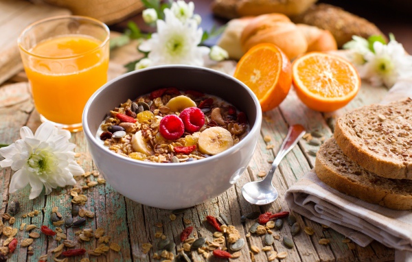 Мюсли в миске с молоком на завтрак с соком и апельсинами 