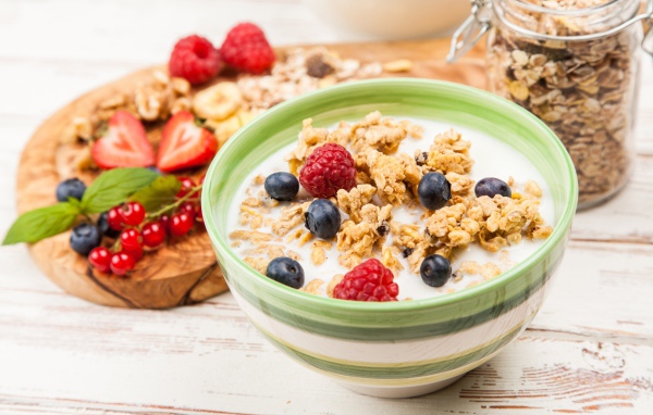 Мюсли с молоком и ягодами на столе к завтраку