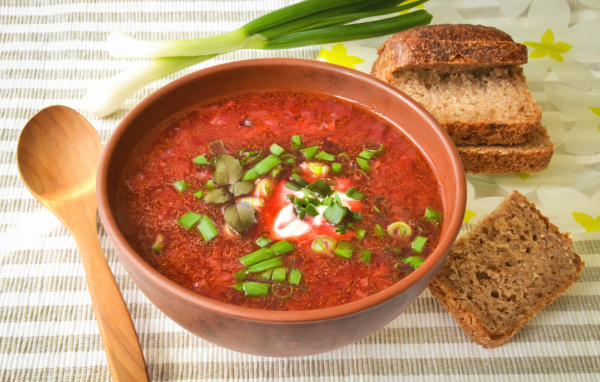 Красный борщ с луком на столе с хлебом 