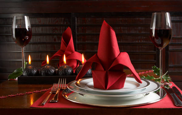 Красная салфетка на тарелке на столе с бокалами вина и свечами