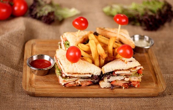 Сэндвичи на доске с картофелем фри и соусом