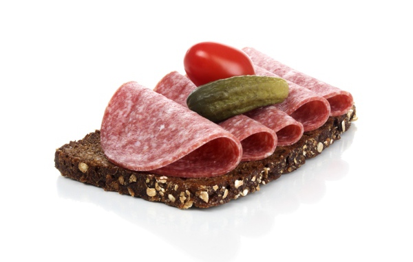 Бутерброд с черным хлебом, колбасой, соленым огурцом и помидором на белом фоне