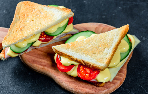 Сэндвич с сыром, помидорами и огурцами на столе