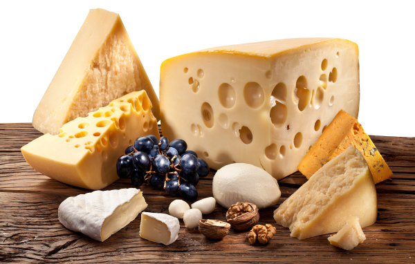 Куски сыра на деревянном столе с виноградом и грецким орехом
