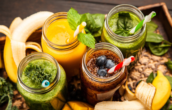 Банки со смузи на столе с бананами