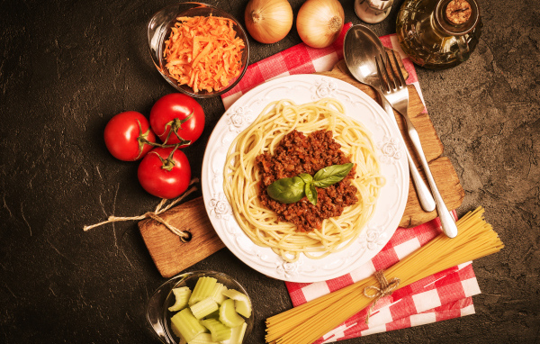 Спагетти с фаршем на столе с овощами