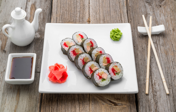 Суши на большой белой тарелке с соусом васаби и имбирем на столе соевым соусом