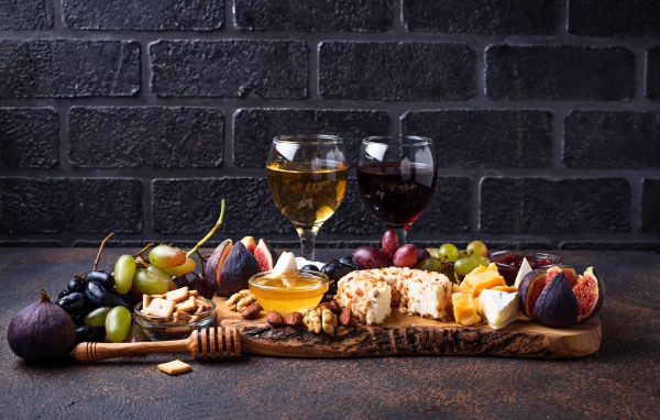 Два бокала вина на столе с сыром, инжиром и виноградом