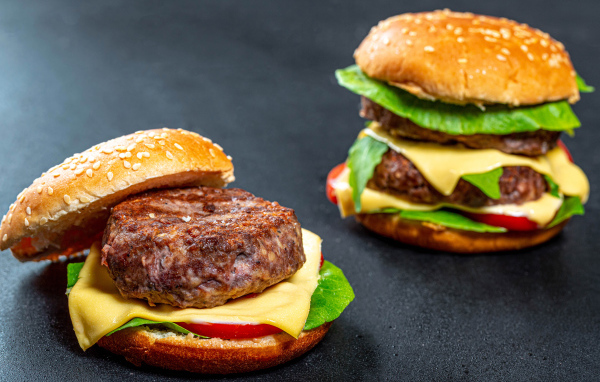 Два гамбургера с большой котлетой на столе