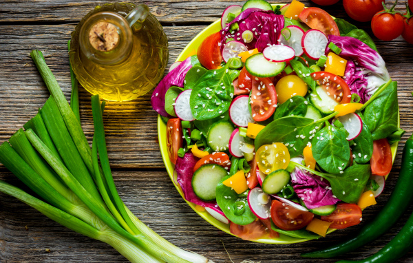 Овощной салат на столе с оливковым маслом и зеленым луком