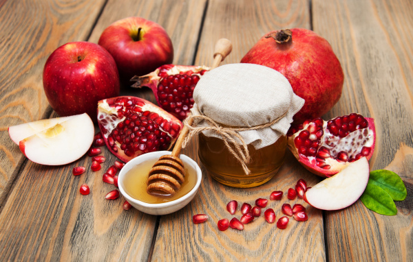 Банка меда на столе с гранатами и яблоками