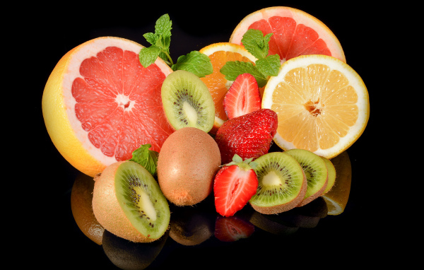 Цитрусовые фрукты на черном фоне с ягодами клубники 
