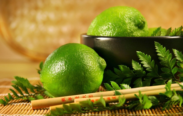 Лаймы на столе с палочками и листьями