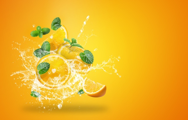 Куски апельсина в брызгах воды на оранжевом фоне
