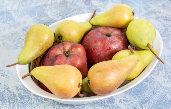 Красные яблок и груши на тарелке на столе