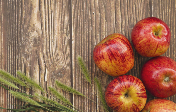 Красные яблоки на деревянном фоне с зелеными колосками