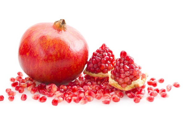 Красный гранат с зернами на белом фоне