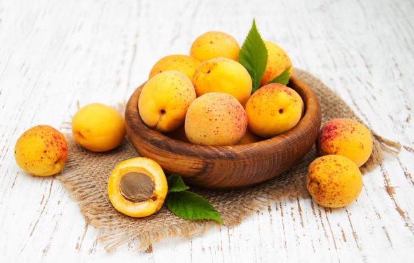 Спелые абрикосы в деревянной миске на столе