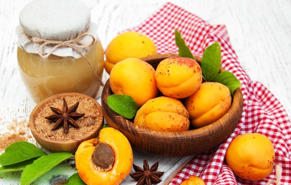 Спелые абрикосы на столе с бадьяном, коричневым сахаром и джемом