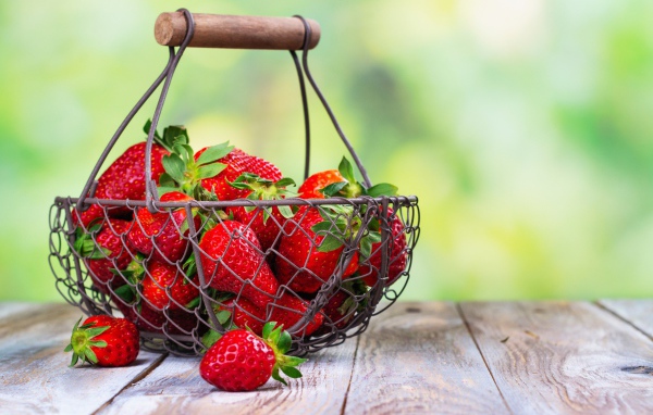 Спелая красная клубника в корзине на столе