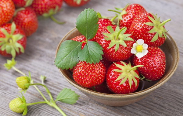 Спелая красная клубника в миске на столе 