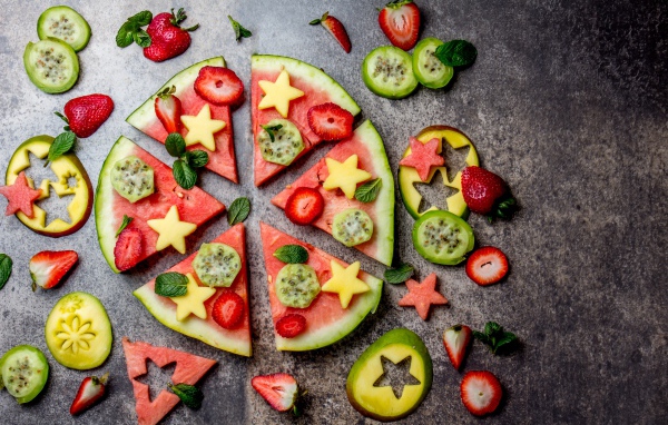 Кусочки арбуза с фруктами на сером фоне