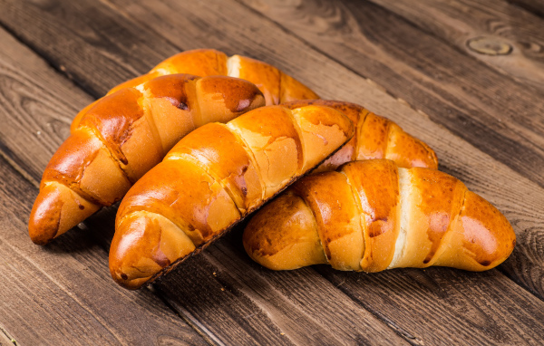 Аппетитные румяные круассаны на деревянном столе 