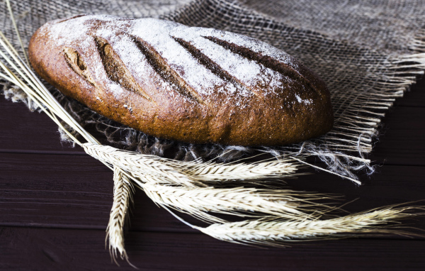 Буханка свежего хлеба на столе с колосьями пшеницы